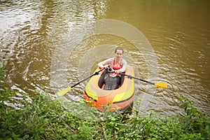 Woman with oars and action camera in a rubber boat