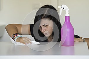 Woman with obsessive compulsive disorder cleaning table with detergents. OCD concept