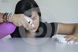 Woman with obsessive compulsive disorder cleaning table with detergents. OCD concept