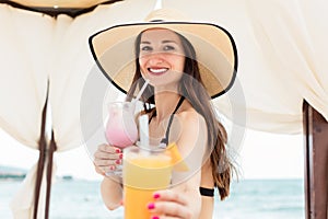 Woman offering a cocktail on the beach as refreshment