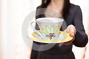 Woman offering a cup of tea blurring