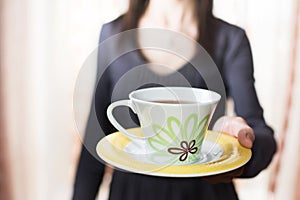 Woman offering a cup of tea blurring