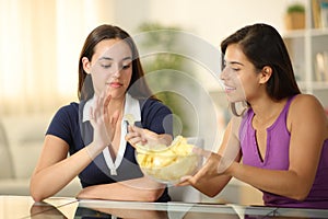 Woman offering potato chips to a friend who refuse it