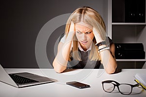 Woman in office holding her head in disgust photo