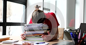 A woman in the office lowers her head to folders, close-up