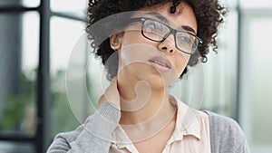 woman in the office is tired of working on the computer. took off her glasses and rubs her neck