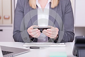 Woman at the office typing and messaging with her mobile phone