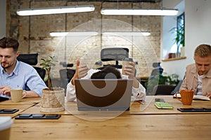 Woman office worker hiding head behind laptop gesturing thumbs up