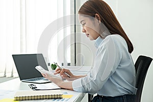 Woman office worker sitting to working and pressing a calculator to calculate the profit of a new business project