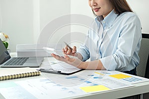 Woman office worker sitting to working and pressing a calculator to calculate the profit of a new business project