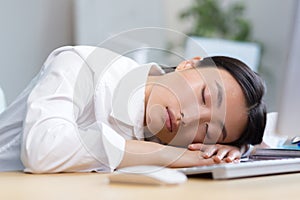 Woman office worker tired Asian sleeps on the desk, overtired sleeps in the day photo