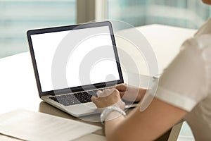 Woman in office working on laptop with mockup blank screen.