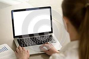 Woman in office working on laptop with mockup blank screen.