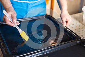 Woman oiling baking sheet. Baking at home.