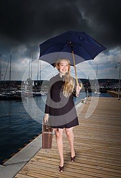 Woman with old suitcase and umbrella at harbor