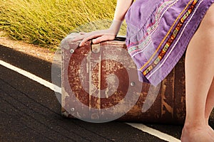 Woman with old vintage suitcase on the road