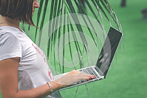 Woman online shopping concept. Freelancer woman in the green park with modern laptop. Bali island.