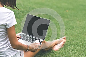 Woman online shopping concept. Woman in the green park with modern laptop. Bali island.