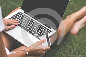 Woman online shopping concept. Woman in the green park with modern laptop. Bali island.