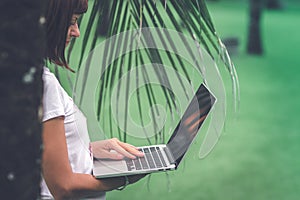 Woman online shopping concept. Woman in the green park with modern laptop. Bali island.