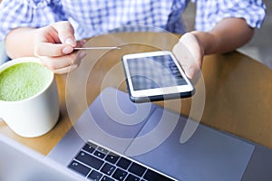 Woman online shopping by credit card payment, using mobile smart phone and laptop computer with blank cell phone screen with