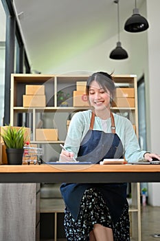 Woman, online store owner, working at her desk, doing a sales accounts report