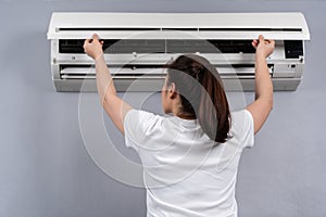 Woman open the air conditioner indoor at home