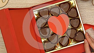 Woman open gift box with heart-shaped chocolate candies aphrodisiac, top view