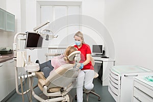 Woman with open mouth having her teeth examined by female dentist. Teeth checkup at dentist`s office.