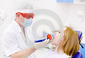 Woman with open mouth receiving dental filling drying proc