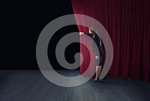 Woman open red curtains of the theater stage