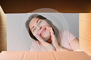 Woman opened a cardboard box with an ordered product and emotionally reacts to its contents, the concept of a postal item, a