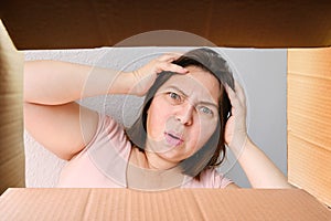 Woman opened a cardboard box with an ordered product and emotionally reacts to its contents, the concept of a postal item, a