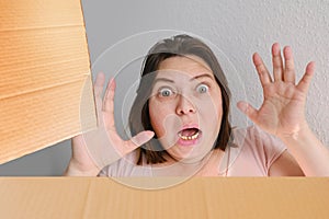 Woman opened a cardboard box with an ordered product and emotionally reacts to its contents, the concept of a postal item, a