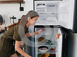 A woman opened the refrigerator and looks sadly into it, wondering what to cook, defrosted the refrigerator, freezer