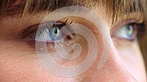 Woman opening blue eyes and blinking, thinking serious thoughts. Close up female with intense stare, in a state of