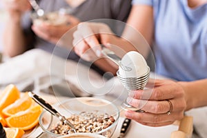 Woman opening a boiled egg for breakfast