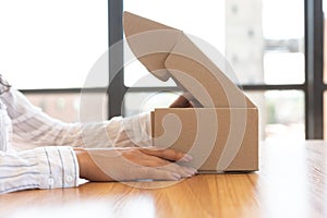 Woman opening box with new parcel, close-up