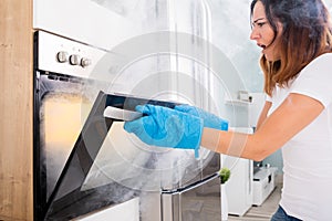 Woman Opening Door Of Oven Full Of Smoke