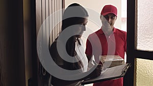 Woman opening door, signing for receiving parcel