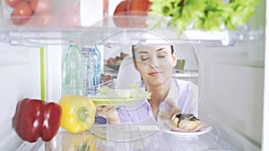 Woman opening the fridge and picking food for her diet