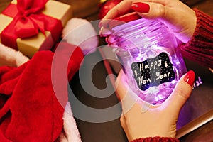 Woman opening a glowing jar with inscription Happy New Year.