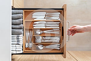 Woman opening kitchen drawer with wooden cutlery tray