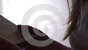 Woman opening pages of the Bible in bright white background