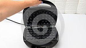 Woman opening waffle maker,baking waffles,pancakes.Morning breakfast food preparation kitchen table.bakery,cusine technology.