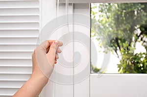 Woman opening white horizontal window blinds