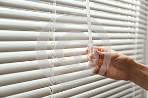 Woman opening window blinds, closeup