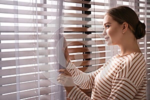 Woman opening window curtain at home in morning