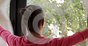 Woman opening window looking at street