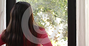 Woman opening window looking at street